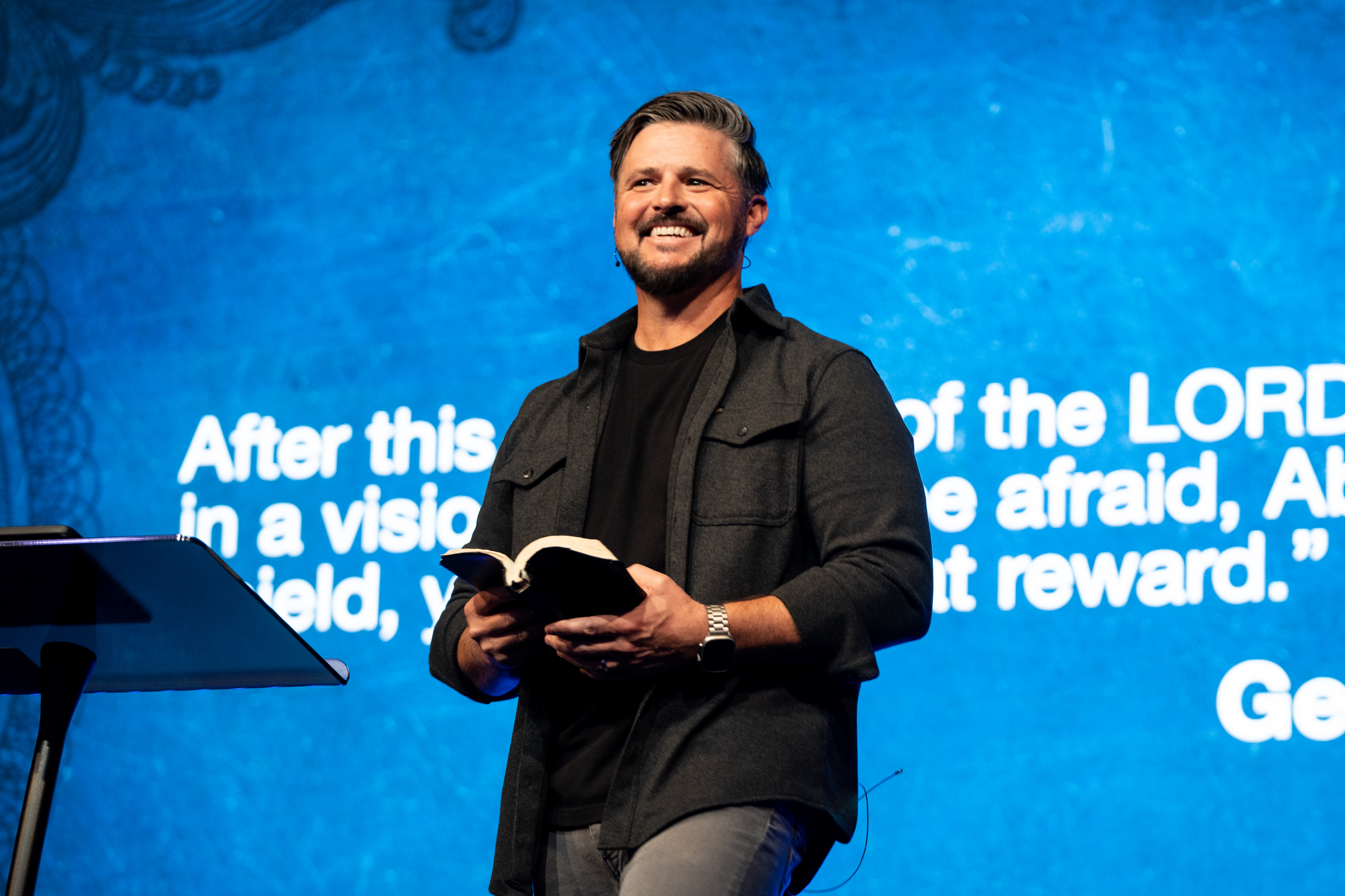 Jarod Smith holding a Bible while speaking on stage