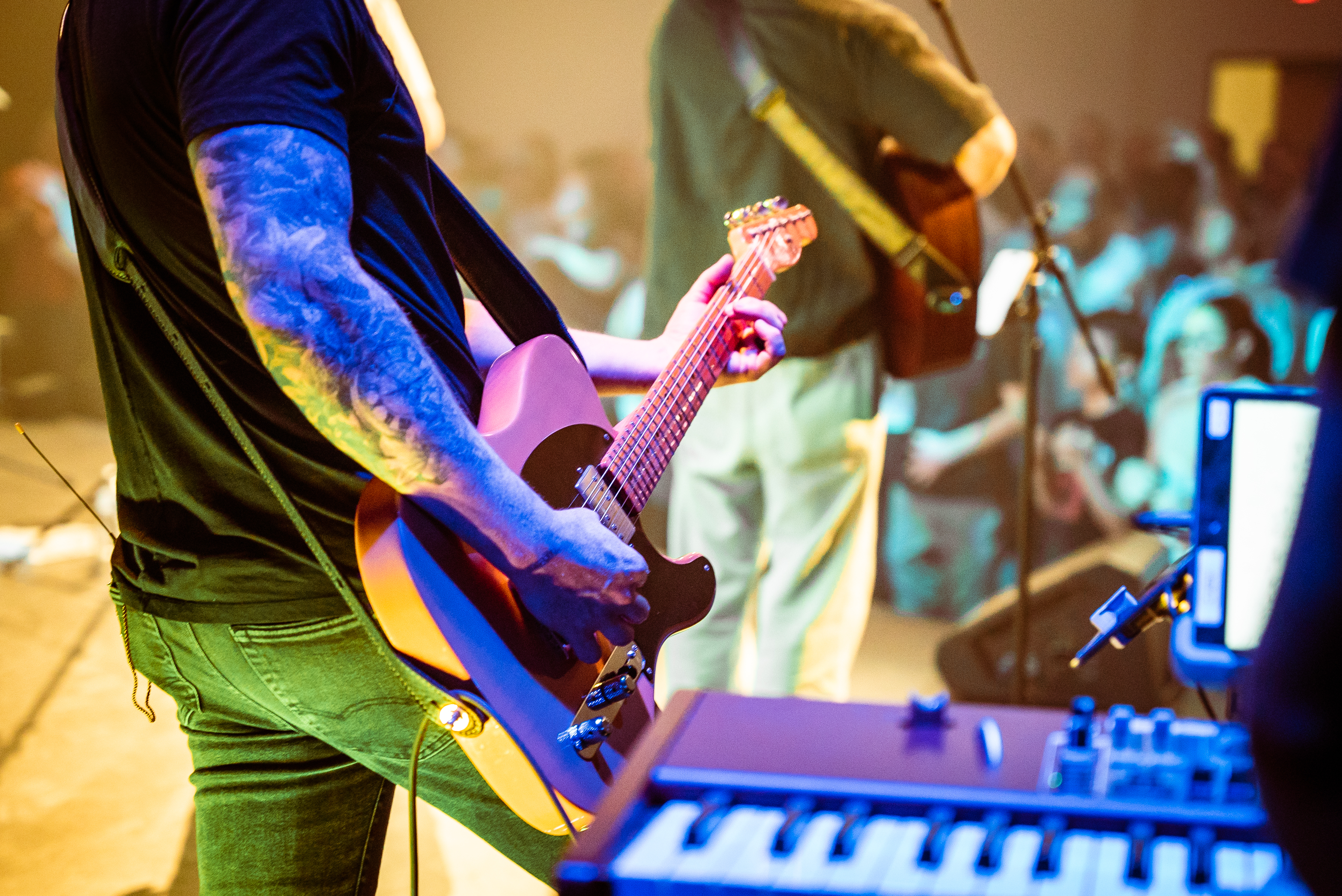 Close-up of an electric guitar played on a dark stage