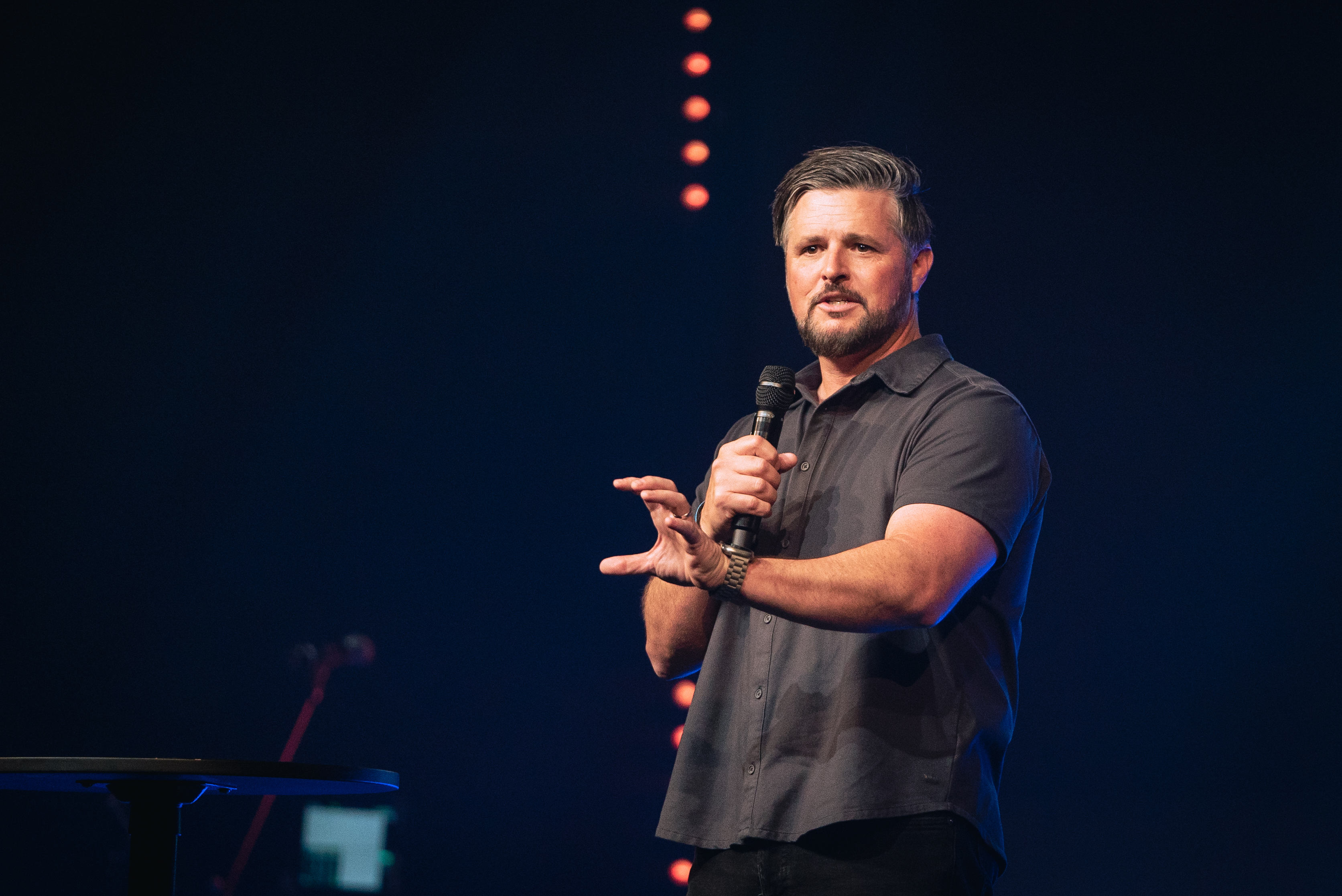 Worship leader singing into a microphone with eyes closed